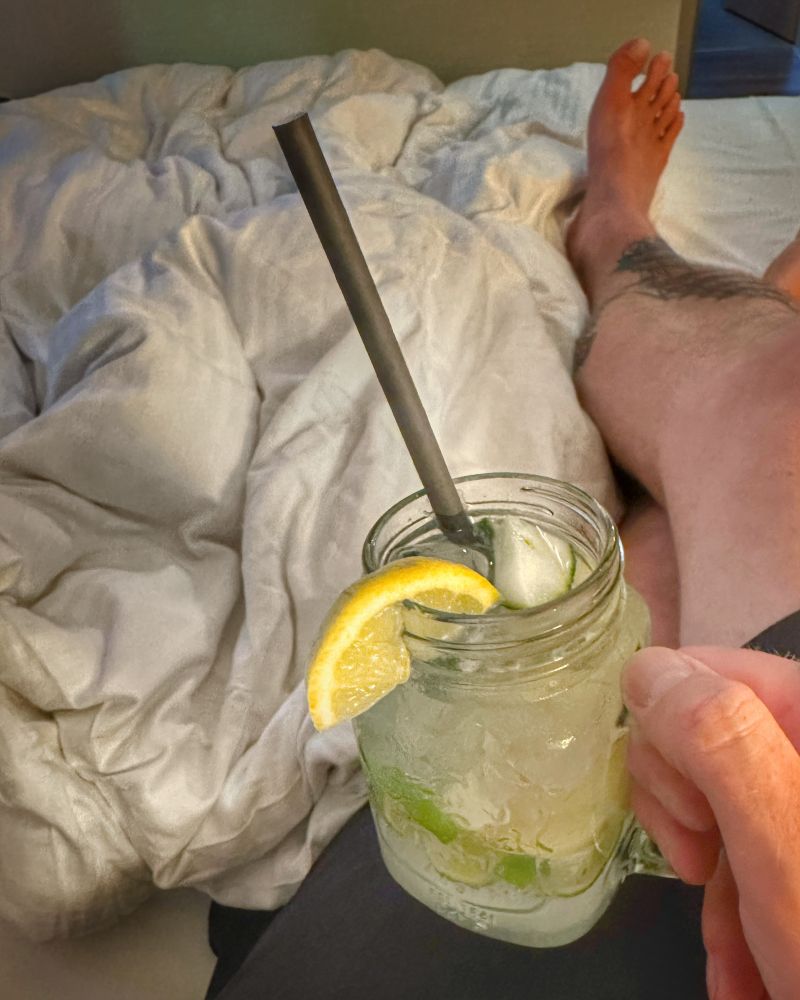 Das Foto zeigt meine Beine auf einen Hotelbett. Im Vordergrund halte ich ein Glas mit einem lecker kalten Moscow Mule.